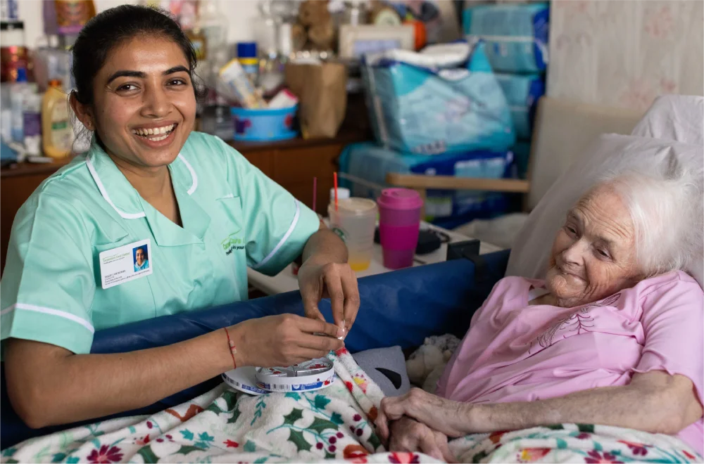 Caretaker talks with an elderly woman in a cozy room.